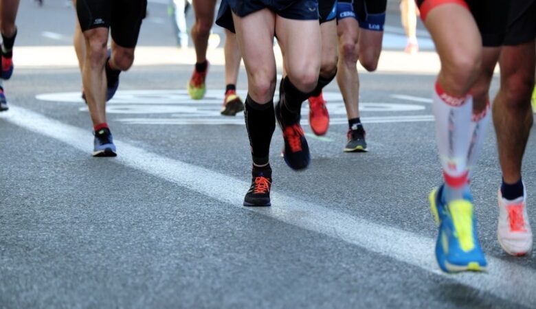 Läufergruppe mit bunten Schuhen auf einer abgesperrten Straße